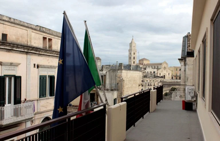 Balcone con bandiere italiana ed europea e veduta di Matera